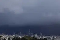 Sun shines on Corona Heights, bottom, as the downtown skyline is obscured by rain clouds in San Francisco, Friday, Feb. 24, 2023. California and other parts of the West are facing heavy snow and rain from the latest winter storm to pound the United States. The National Weather Service has issued blizzard warnings for the Sierra Nevada and Southern California mountains. (AP Photo/Jeff Chiu)