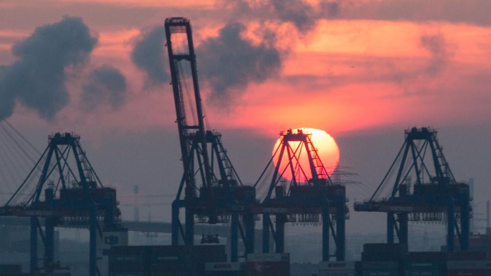 Die Sonne geht im Hafen hinter den Containerbrücken des HHLA Containerterminal Tollerort unter.