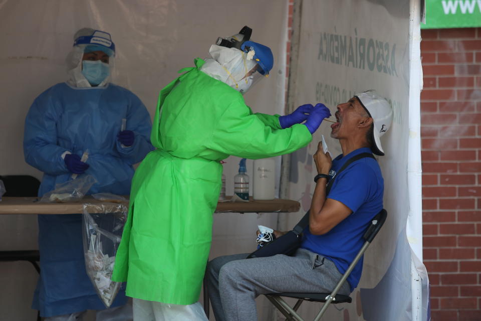 A healthcare worker tests a person for the new coronavirus inside a diagnostic tent in Mexico City, Saturday, Nov. 14, 2020. Mexico City announced yesterday that restaurants and bars will have to close earlier after the number of people hospitalized for COVID-19 rose to levels not seen since August. (AP Photo/Ginnette Riquelme)