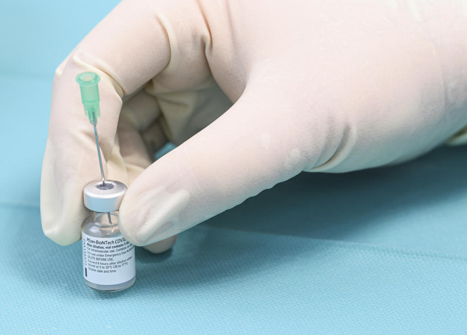 A helper prepares vaccine against Covid-19 from Biontech/Pfizer for a vaccination in a so-called "rolling vaccination centre", which is in Bannewitz, Germany, near Dresden for a test run on Friday, Feb. 19, 2021. Starting this weekend, such vaccination centres will be used in three Saxon municipalities. (Robert Michael/dpa via AP)