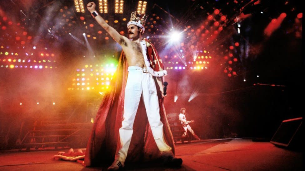 Freddie Mercury en el escenario con corona y capa en el estadio de Wembley, 1986