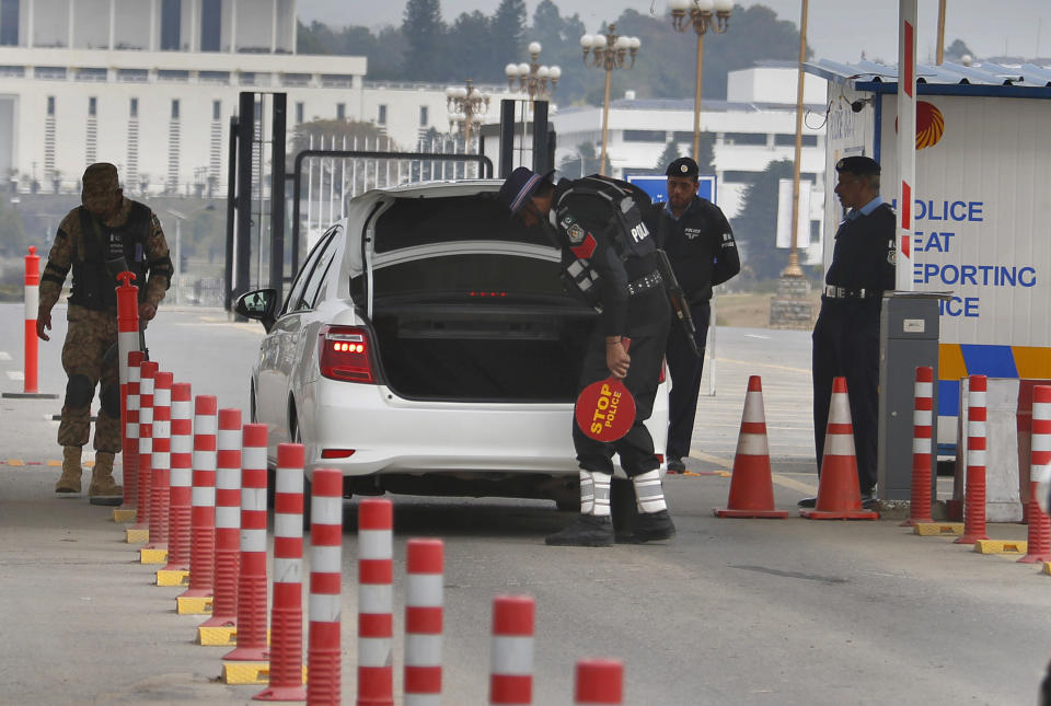 A Pakistani army soldier stands guard while police officers search a vehicle at a checkpoint near presidency to ensure security ahead of Saudi Arabia's crown prince visit to Pakistan, in Islamabad, Pakistan, Sunday, Feb. 17, 2019. Saudi Crown Prince Mohammed bin Salman will arrive in Islamabad on Sunday evening on an official visit that is expected to include the signing of agreements for billions of dollars of investment in Pakistan. (AP Photo/Anjum Naveed)