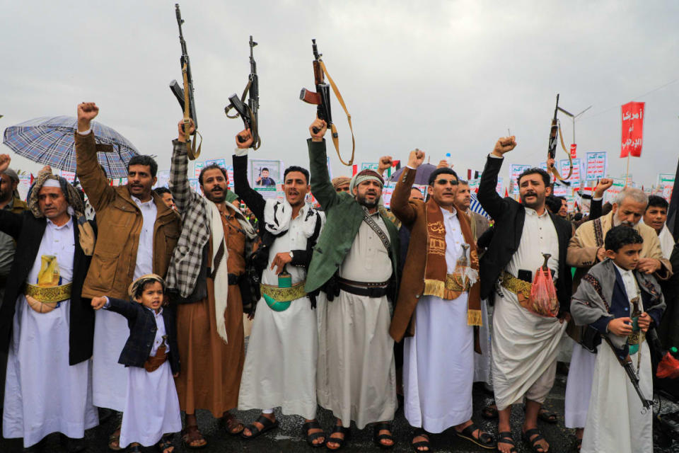 People lift rifles and placards as they chant during an anti-Israel and anti-US rally in the Huthi-controlled capital Sanaa on January 19, 2024, 