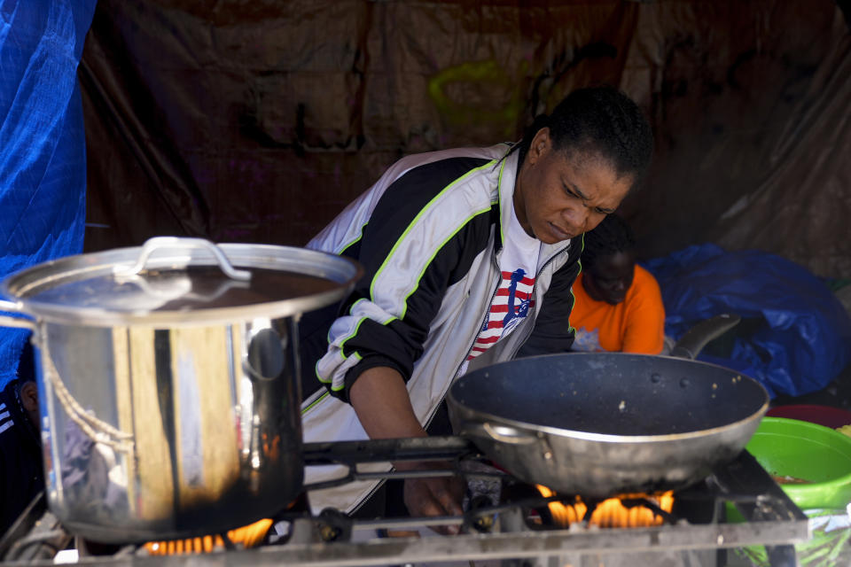 Monique Mupepe, from Congo, adjusts the flame in a kitchen area of an encampment of asylum-seekers mostly from Venezuela, Congo and Angola next to an unused motel owned by the county, Wednesday, June 5, 2024, in Kent, Washington. The group of about 240 asylum-seekers is asking to use the motel as temporary housing while they look for jobs and longer-term accommodations. (AP Photo/Lindsey Wasson)