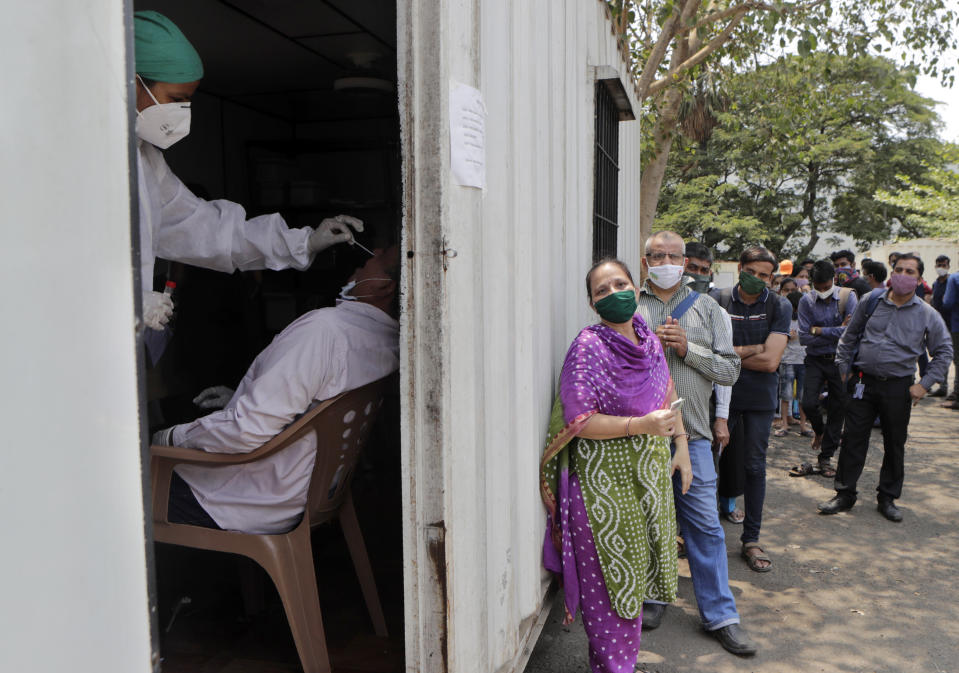 A health worker takes a nasal swab sample of a person to test for COVID-19 as others wait for their turn outside a field hospital in Mumbai, India, Thursday, May 6, 2021. Infections in India hit another grim daily record on Thursday as demand for medical oxygen jumped seven-fold and the government denied reports that it was slow in distributing life-saving supplies from abroad. (AP Photo/Rajanish kakade)