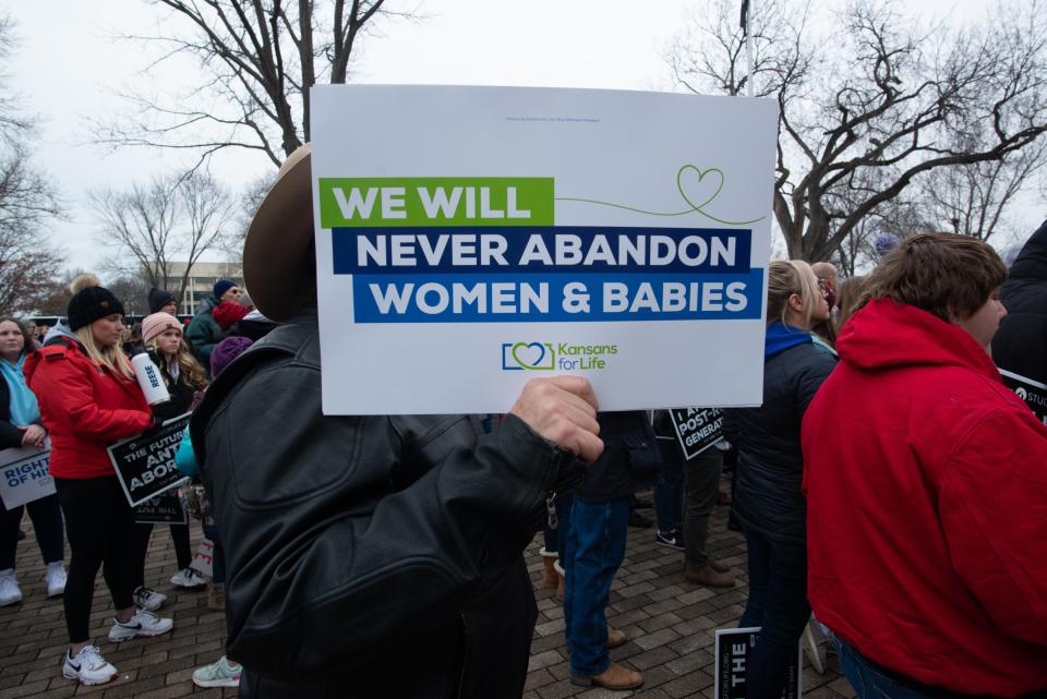 A man holds an anti-abortion sign from the organization Kansans for Life during Tuesday's March for Life event at the Kansas Statehouse.