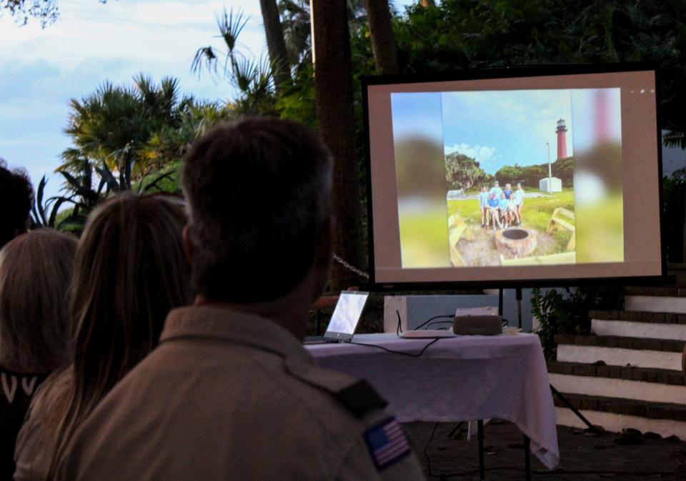 Mia Stahl's parents, Brooke and Michael Stahl, watch a slideshow at a ceremony on Dec. 10, 2023 at the Jupiter Inlet Lighthouse Outstanding Natural Area, with a slide showing their daughter's Eagle Scout project, benches and a fire pit near the lighthouse.