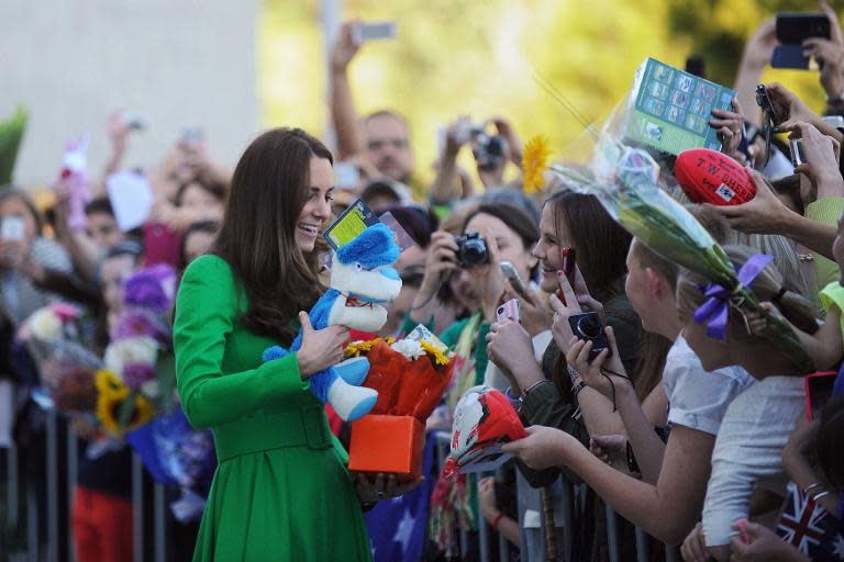 Catherine, the Duchess of Cambridge (L), receives presents as she greets the public after visiting the National Portrait Gallery in Canberra on April 24, 2014