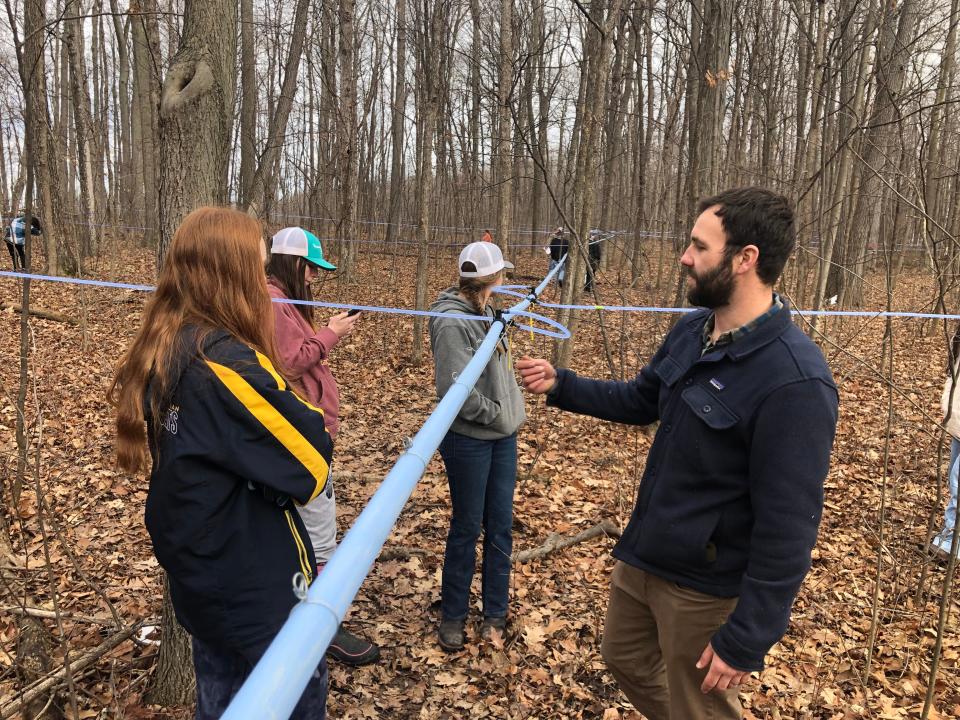 Marcus Whitman environmental science teacher Jon Pragle and students inspect the tubes that carry sap from maple trees to the school's new sugarhouse.