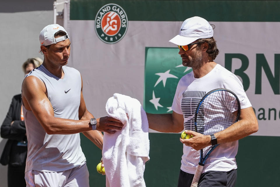 Spain's Rafael Nadal, left, takes his towel from coach Carlos Moya during a training session at Roland Garros stadium ahead of the French Open tennis tournament in Paris, Thursday, May 27, 2021. (AP Photo/Michel Euler)