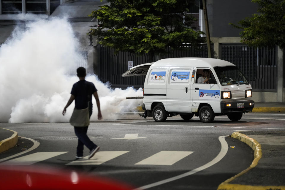 Workers fumigate streets against dengue-promoting mosquitoes in the Altamira neighborhood of Caracas, Venezuela, Tuesday, Dec. 12, 2023. (AP Photo/Matias Delacroix)