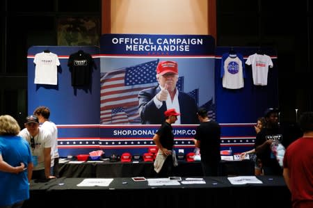 Members of the audience walk by a merchandise table as U.S. President Donald Trump delivers remarks at a Keep America Great rally at the Santa Ana Star Center in Rio Rancho, New Mexico