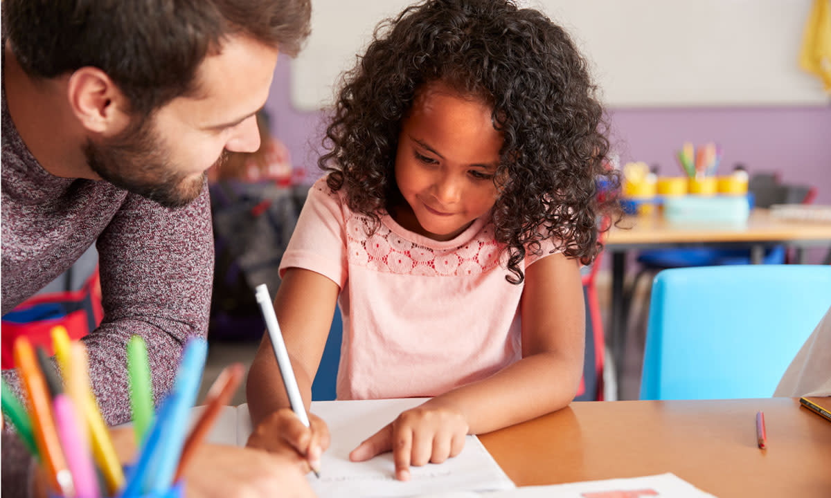 This is a photo of a teacher helping a student at their desk.