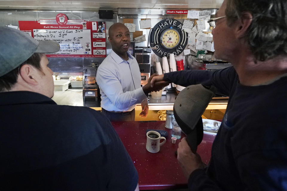Sen. Tim Scott, R-S.C., shakes hands with diners at the breakfast counter during a visit to the Red Arrow Diner, Thursday, April 13, 2023, in Manchester, N.H. Scott on Wednesday launched an exploratory committee for a 2024 GOP presidential bid, a step that comes just shy of making his campaign official. (AP Photo/Charles Krupa)