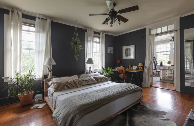 A light-filled bedroom with gray walls and hardwood flooring.