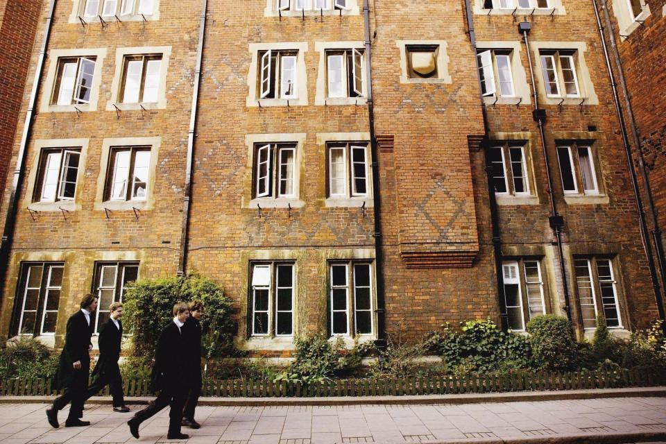 <p>Pupils at Eton College hurry between lessons, wearing the school uniform of tailcoats and starched collars</p> (Getty Images)