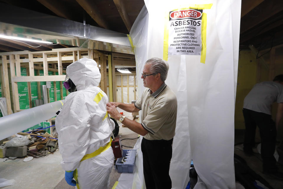 File - In this Oct. 18, 2017, file photo, George Riegel, Jr., M.D., right, owner of Asbestos Removal Technologies Inc., helps prepare a personal air monitor on job forman Megan Eberhart before asbestos abatement in Howell, Mich. Congress ordered the EPA in 2016 to gauge risks of asbestos and nine other highly toxic substances and find better ways to manage them for public safety. (AP Photo/Paul Sancya, File)