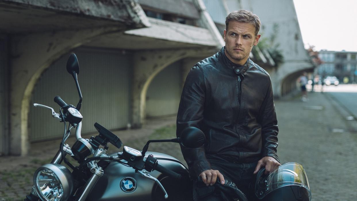 Sam Heughan as Danny sits on motorbike