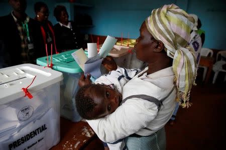 A women carrying her baby casts her vote in Gatundu in Kiambu county, Kenya August 8, 2017. REUTERS/Baz Ratner