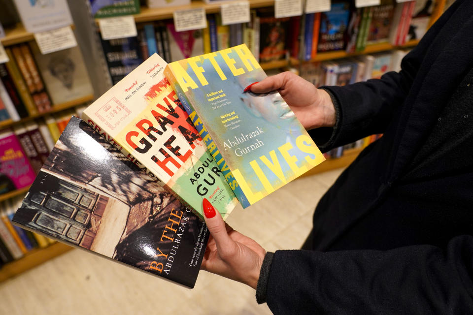 A member of staff holds copies of books by Zanzibar-born novelist Abdulrazak Gurnah in a book shop in London, Thursday, Oct. 7, 2021. U.K.-based Tanzanian writer Abdulrazak Gurnah, whose experience of crossing continents and cultures has fed his novels about the impact of migration on individuals and societies, won the Nobel Prize for Literature on Thursday. (AP Photo/Alberto Pezzali)