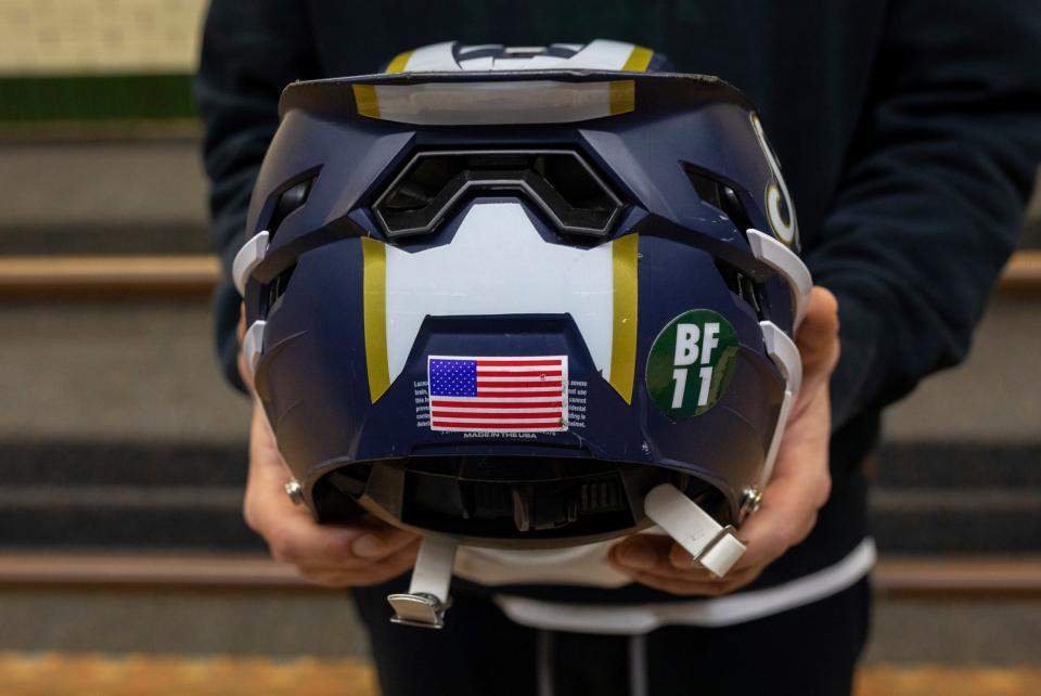 Brian Fraser's former lacrosse coach, Justin Macksoud, holds a helmet with a Spartan green 