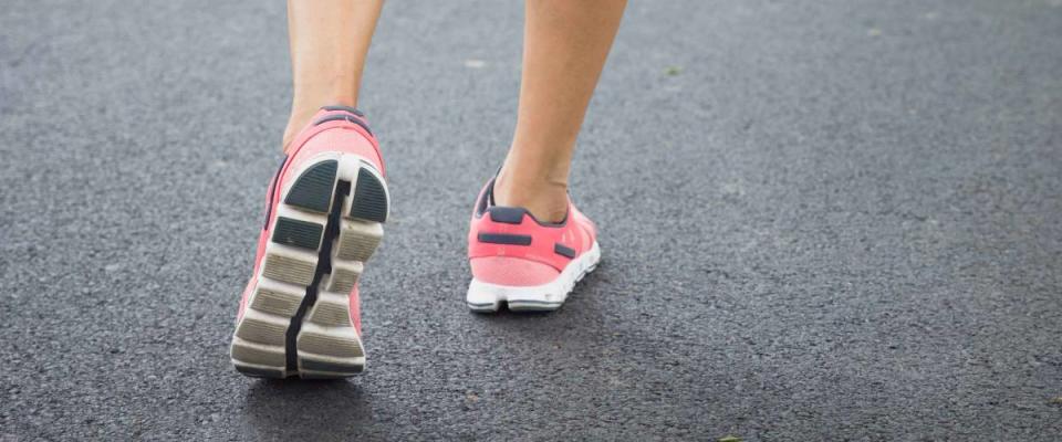 Close up shoes, legs. sport runner woman back view running, slowing down.