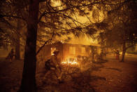 FILE - In this Nov. 9, 2018, file photo, firefighters work to keep flames from spreading through the Shadowbrook apartment complex as a wildfire burns through Paradise, Calif. Pacific Gas and Electric says it has reached a $13.5 billion settlement that will resolve all major claims related to devastating wildfires blamed on its outdated equipment and negligence. The settlement, which the utility says was reached Friday, Dec. 6, 2019, still requires court approval. (AP Photo/Noah Berger, File)