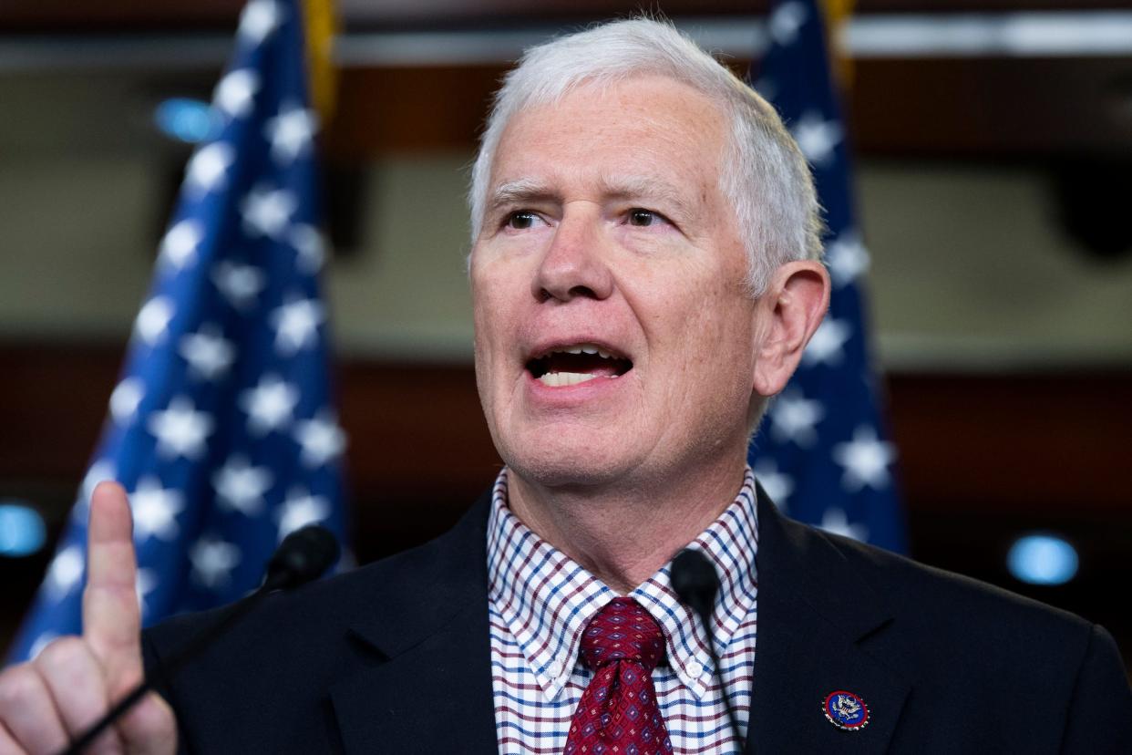 Republican Rep. Mo Brooks of Alabama, his right index finger raised, addressed a Capitol Hill press conference while standing against a backdrop of several American flags.