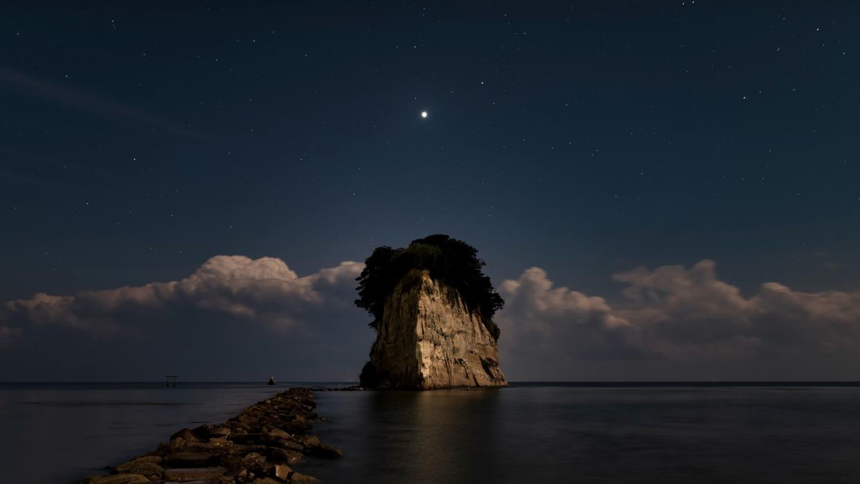  venus in the night sky above a rock in the ocean 