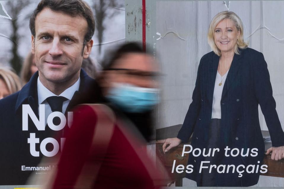 A woman passes by electoral campaign posters of Emmanuel Macron and Marine Le Pen (AFP/Getty)