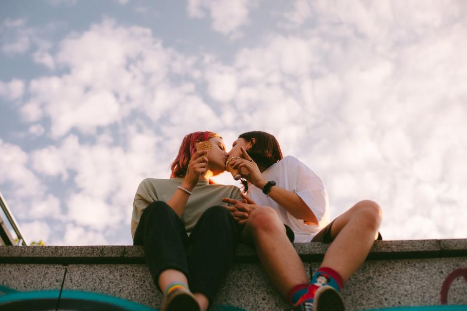 lesbian couple kissing while sitting in the city during summer