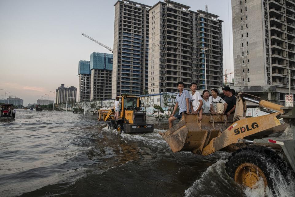 People are evacuated on bulldozers and trucks amid flooding