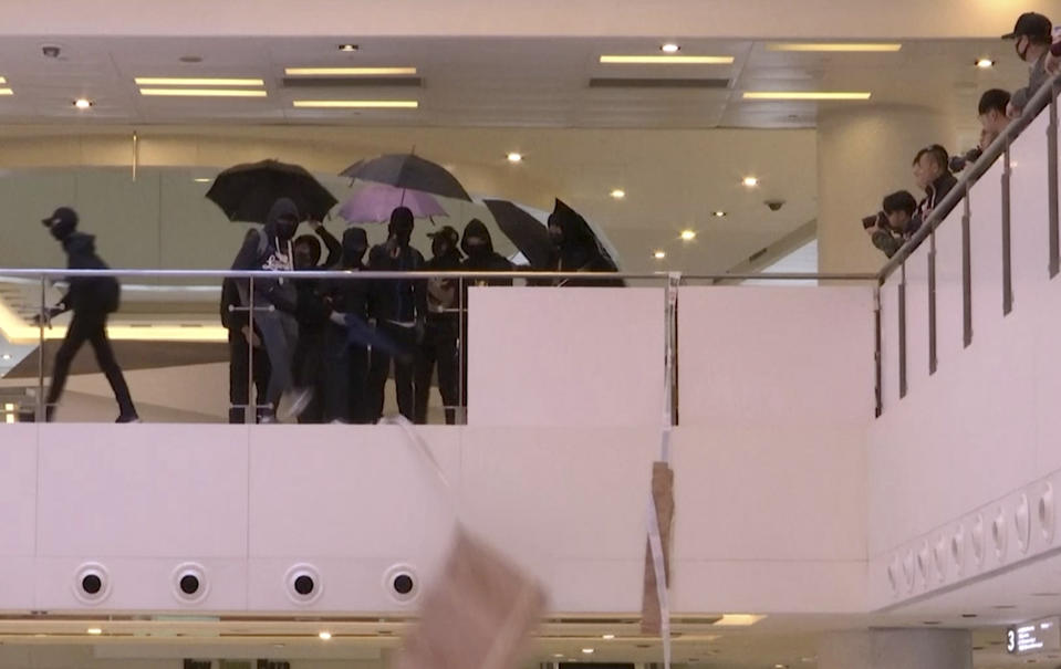 In this image made from video, masked protesters are seen at a shopping mall in Sha Tin district in Hong Kong, Sunday, Dec. 15, 2019. Protesters were seen destroying some pro-China shops inside the mall, what led to minor scuffles with riot police and resulted in several arrests on Sunday.(AP Photo)