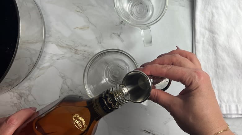 hand pouring rum into jigger