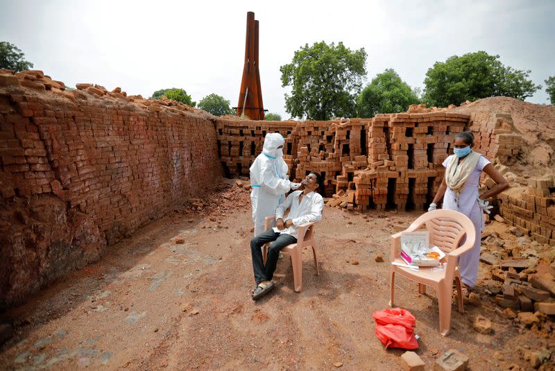 Healthcare worker wearing PPE takes swab in village Rajoda