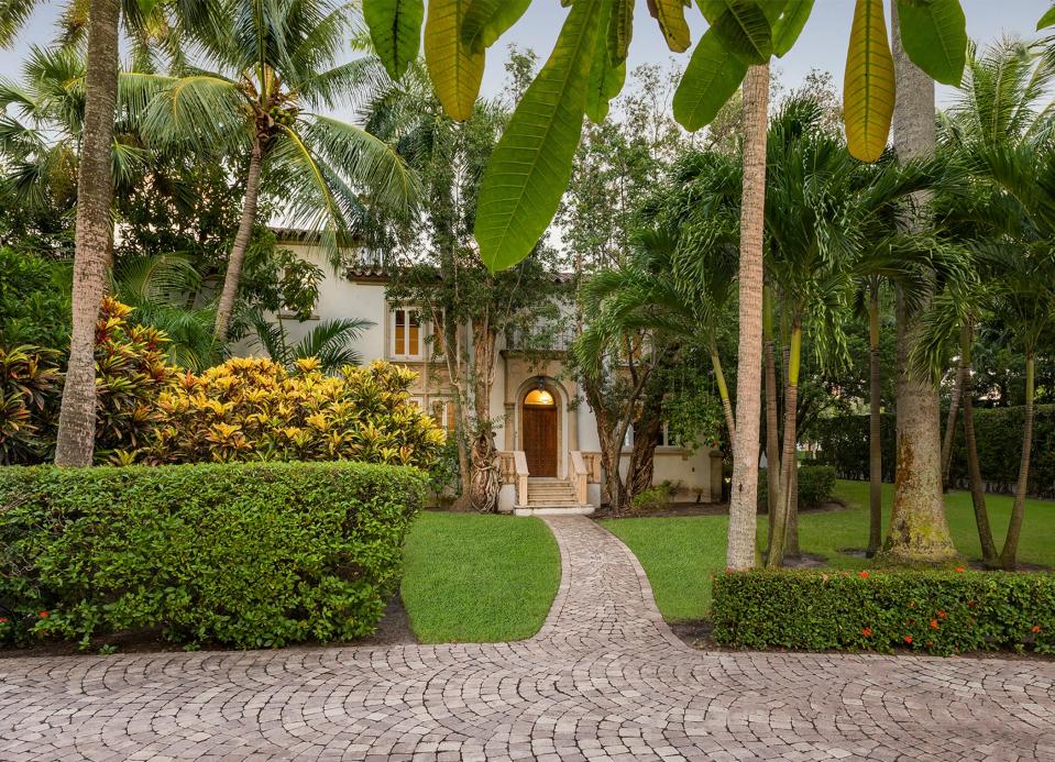 From the driveway, a paved walkway leads to a set of stairs and a door that opens directly into the living room.