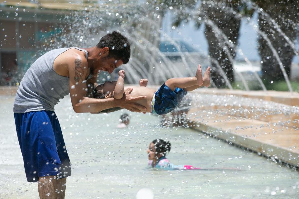 Joe Garcia swings his 1-year-old son, Jovanni, in a stream of water at Bayfront Park's interactive fountain Thursday, July 6, 2023.