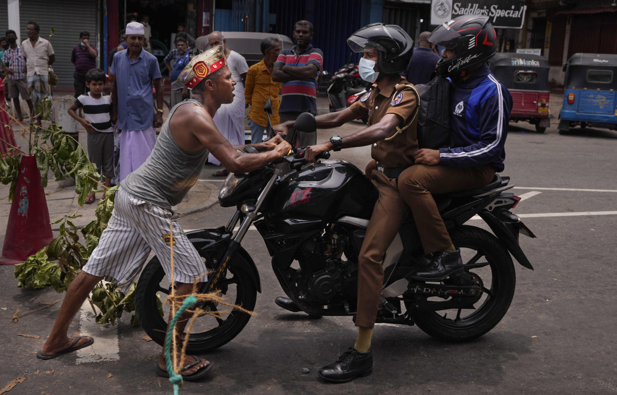 A Sri Lankan man pushes back a police motorbike without allowing the same to proceed as protestors demanding supply of essentials block an intersection for the second consecutive day in Colombo, Sri Lanka, Sunday, May 8, 2022. Diplomats and rights groups expressed concern Saturday after Sri Lankan President Gotabaya Rajapaksa declared a state of emergency and police used force against peaceful protesters amid the country's worst economic crisis in recent memory. (AP Photo/Eranga Jayawardena)