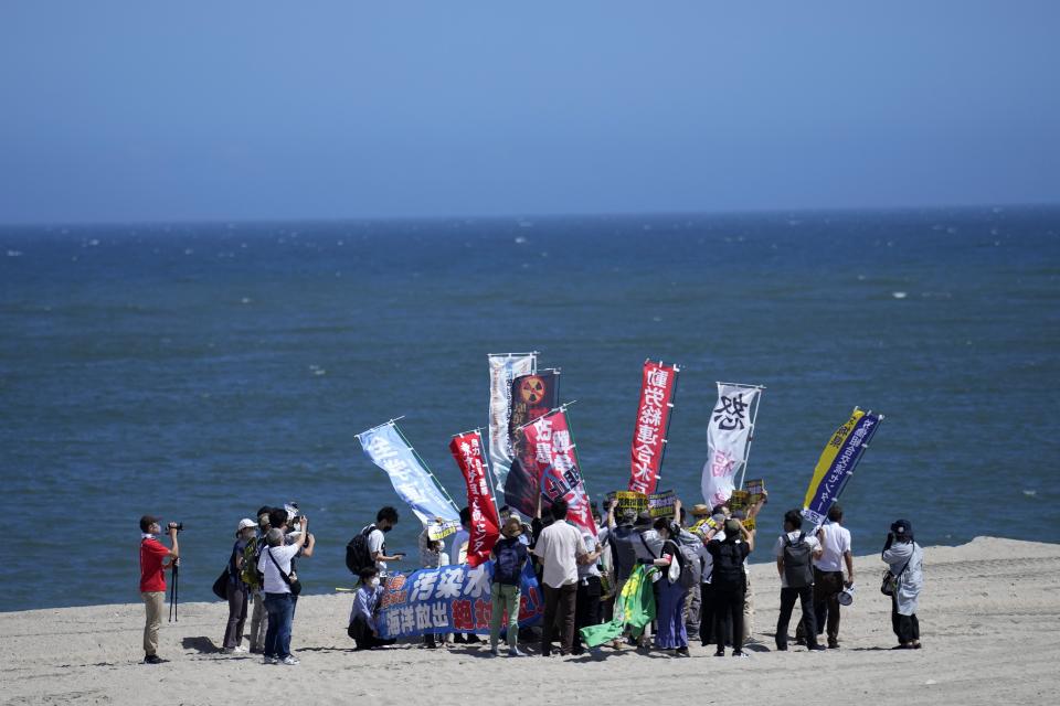 People protest at a beach toward the Fukushima Daiichi nuclear power plant, damaged by a massive March 11, 2011, earthquake and tsunami, in Namie town, northeastern Japan, Thursday, Aug. 24, 2023. The operator of the tsunami-wrecked Fukushima Daiichi nuclear power plant says it began releasing its first batch of treated radioactive water into the Pacific Ocean on Thursday — a controversial step, but a milestone for Japan's battle with the growing radioactive water stockpile. The banner, seen at right, reads: Oppose to the release of the treated radioactive water into the ocean. (AP Photo/Eugene Hoshiko)