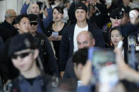 Los Angeles Dodgers Shohei Ohtani, center, walks with his wife Mamiko Tanaka, center left, through a terminal during the baseball team's arrival at Incheon International Airport, Friday, March 15, 2024, in Incheon, South Korea, ahead of the team's baseball series against the San Diego Padres. (AP Photo/Ahn Young-joon)