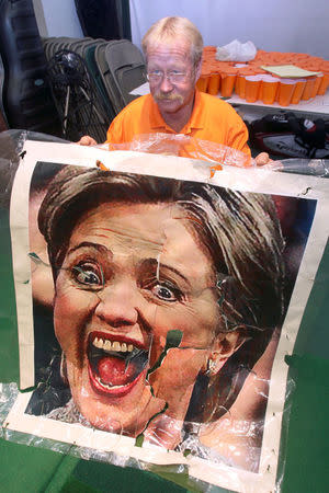 Mike Williams, owner of the Alpine Target Golf Center, holds a large portrait of U.S. Democratic presidential nominee Hillary Clinton that had to be replaced, at the center in Longview, Texas November 2, 2016. The center is holding an informal election poll by letting its golfers hit golf balls at hay bales covered with the portraits of U.S. presidential nominees Clinton and Donald Trump. REUTERS/Todd Yates