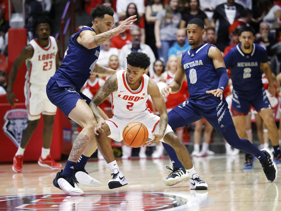 New Mexico guard Donovan Dent, center, is pressured by Nevada forward K.J. Hymes, left, and guard Hunter McIntosh, front right, during the first half of an NCAA college basketball game, Sunday, Jan. 28, 2024, in Albuquerque, N.M. (AP Photo/Eric Draper)