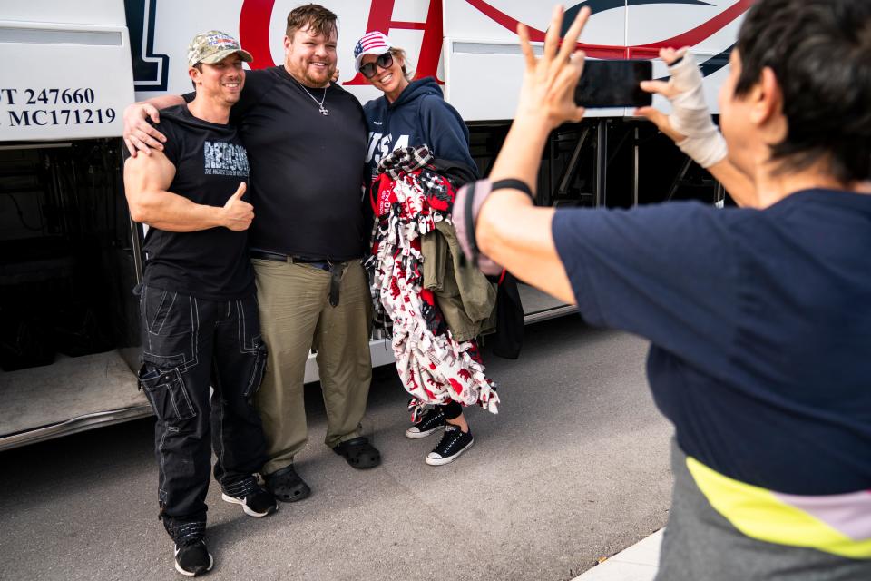 From left to right, Aaron Bathory, Nick Collins, and Patty Cummings pose for a photo in a parking lot across from Oakes Farms Seed to Table Market in North Naples after returning from Washington, D.C., on Thursday, Jan. 7, 2021.