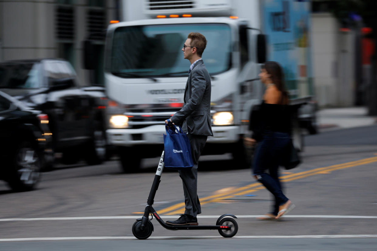 A man in a suit rides an electric BIRD rental scooter along a city street in San Diego, California, U.S. September 4, 2018.REUTERS/Mike Blake