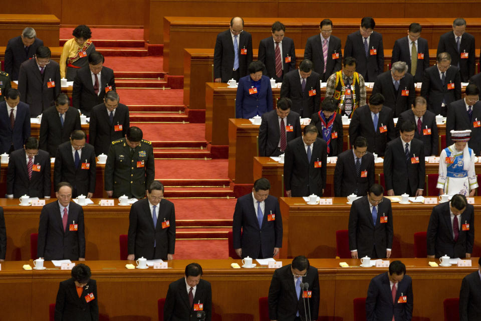 China's top leaders including Chinese President Xi Jinping, center, bow their heads to observe a minute of silence to commemorate the victims of the recent slashing incident in Kunming province during the opening session of the annual National People's Congress in Beijing's Great Hall of the People, China, Wednesday, March 5, 2014. (AP Photo/Ng Han Guan)