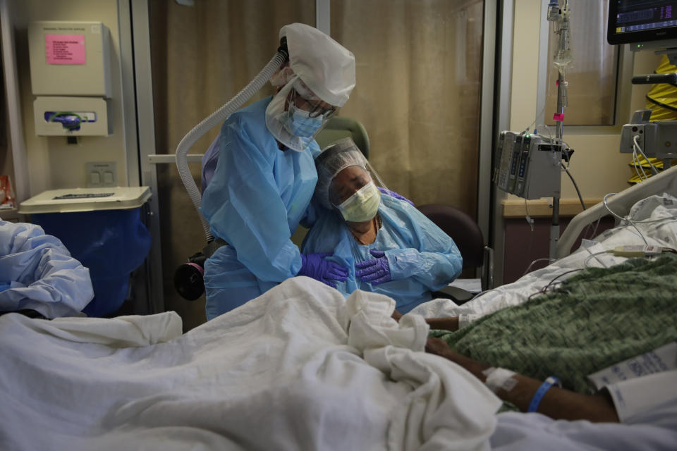 FILE - In this July 31, 2020, file photo, Romelia Navarro, right, is comforted by nurse Michele Younkin as she weeps while sitting at the bedside of her dying husband, Antonio, in St. Jude Medical Center's COVID-19 unit in Fullerton, Calif. California's coronavirus death toll reached 70,000 people, on Monday, Oct. 11, 2021. (AP Photo/Jae C. Hong, File)