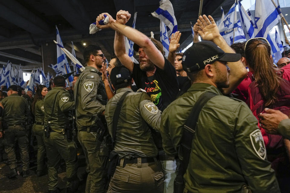 Israeli border police officers disperse demonstrators trying to block the entrance to Israel's main international airport during a protest against plans by Prime Minister Benjamin Netanyahu's government to overhaul the judicial system, at Ben Gurion Airport in Lod, near Tel Aviv, Israel, Monday, July 3, 2023. Thousands of Israelis blocked traffic and snarled movement at the country's main international airport. (AP Photo/Ohad Zwigenberg)