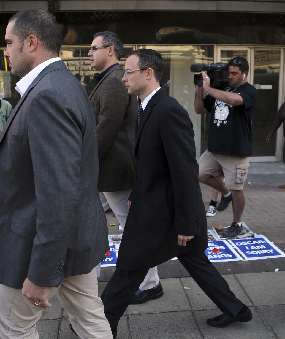 A TV cameraman follows Oscar Pistorius, third left, accompanied by his relatives walking towards the high court in Pretoria, South Africa, Tuesday, April 8, 2014. Pistorius, who is charged with murder for the shooting death of his girlfriend, Reeva Steenkamp, on Valentines Day in 2013, was testifying for a second day at his murder trial Tuesday, answering questions from his defense lawyer. (AP Photo/Themba Hadebe)