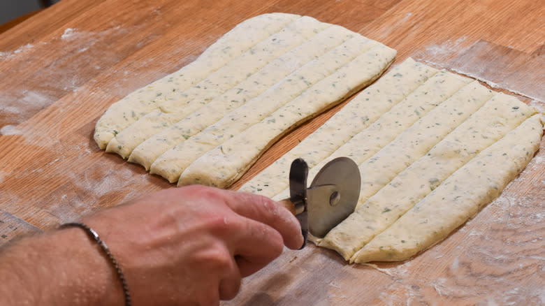 cutting breadstick dough in strips with pizza cutter