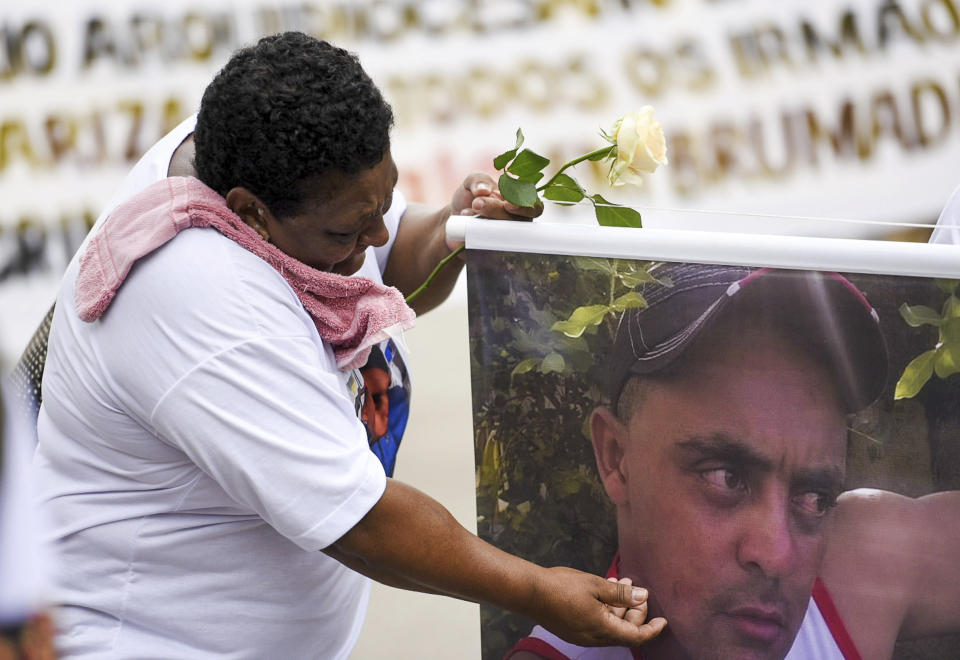 A relative holds a photo of a victim during a tribute to those who died in the dam disaster last year in Brumadinho city, Minas Gerais state, Brazil, Saturday, Jan.25, 2020. The wave of mud and debris that on Jan. 25, 2019 buried the equivalent of 300 soccer pitches and killed 270 people, continues to barrel over residents' minds, the local economy and the environment, one year later. (AP Photo/Gustavo Andrade)